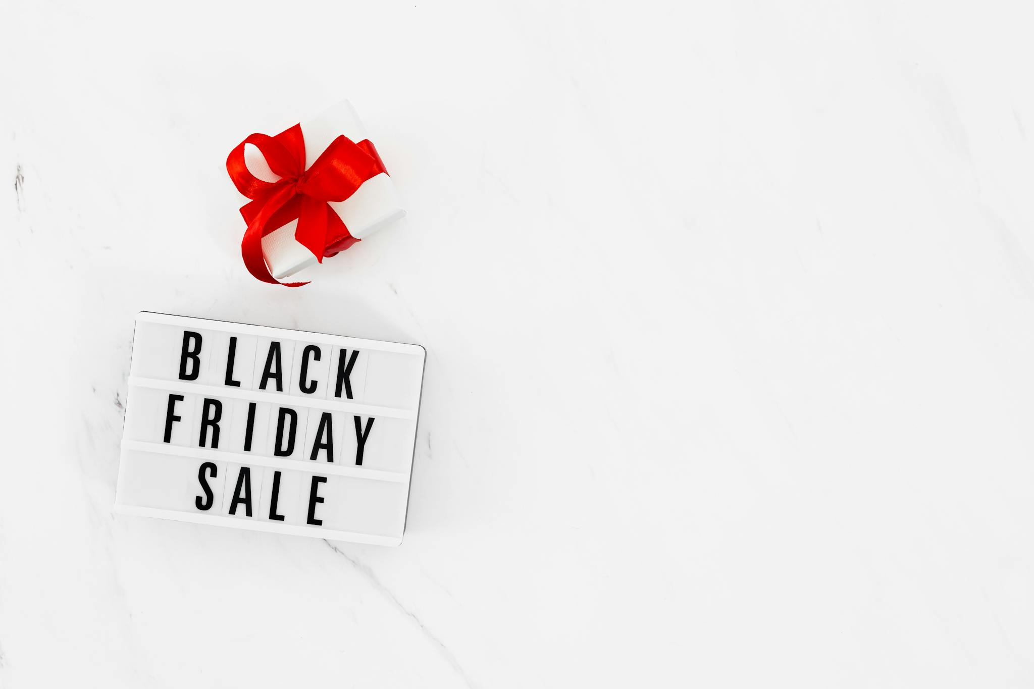 White background with Black Friday sale sign and red ribboned gift box for promotions.